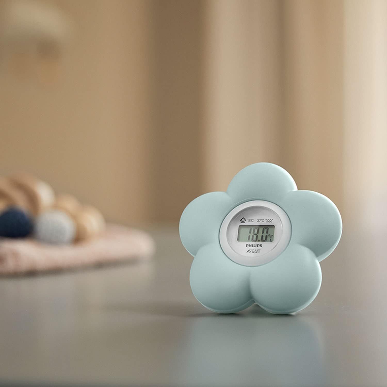 Flower-shaped thermometer on a table with a soft-focus background.